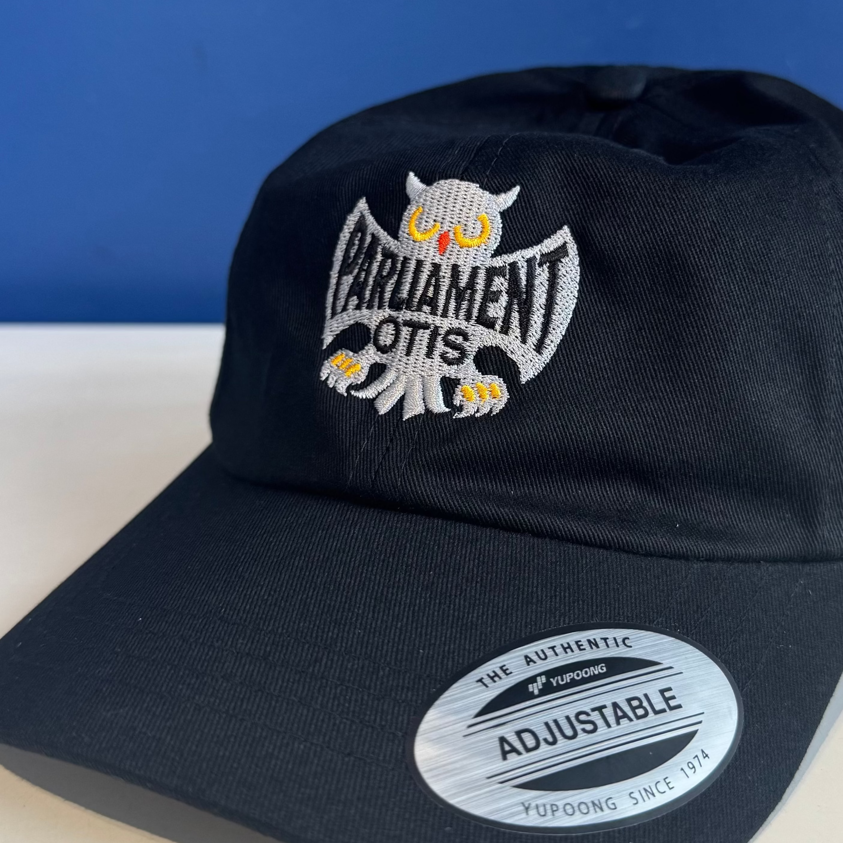 Black cap with owl logo and 'Parliament Otis' text on a blue background
